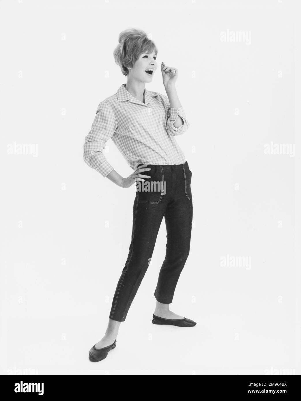 Ritratto a tutta lunghezza di un modello in una camicia a quadri e jeans corti in posa per la fotocamera. Foto Stock