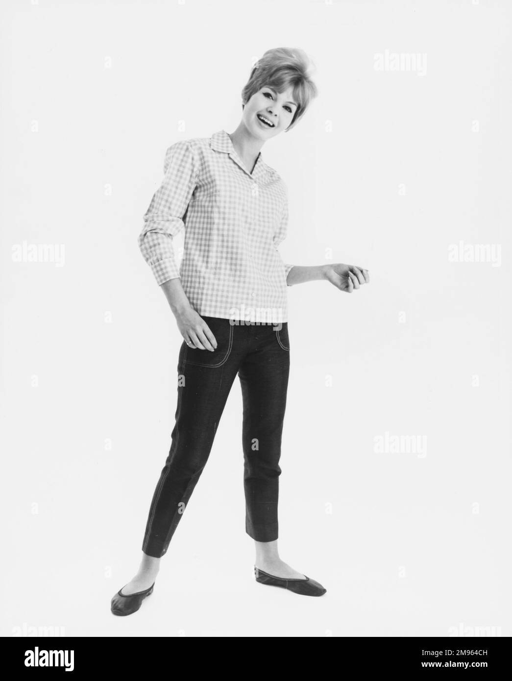 Ritratto a tutta lunghezza di un modello in una camicia a quadri e jeans corti in posa per la fotocamera. Foto Stock