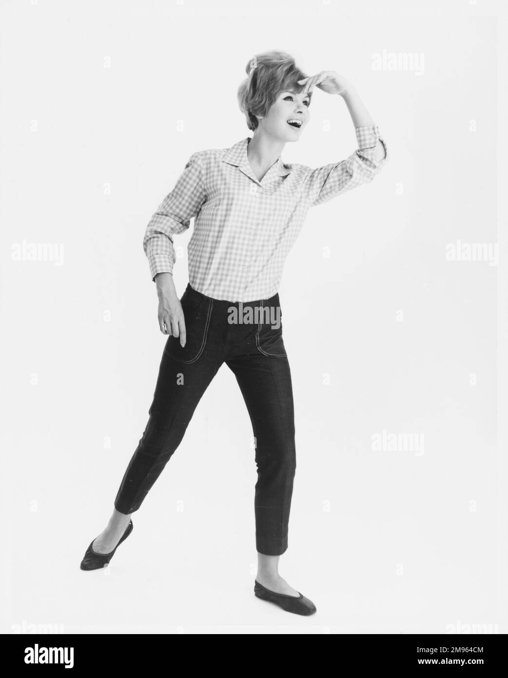 Ritratto a tutta lunghezza di un modello in una camicia a quadri e jeans corti in posa per la fotocamera. Foto Stock