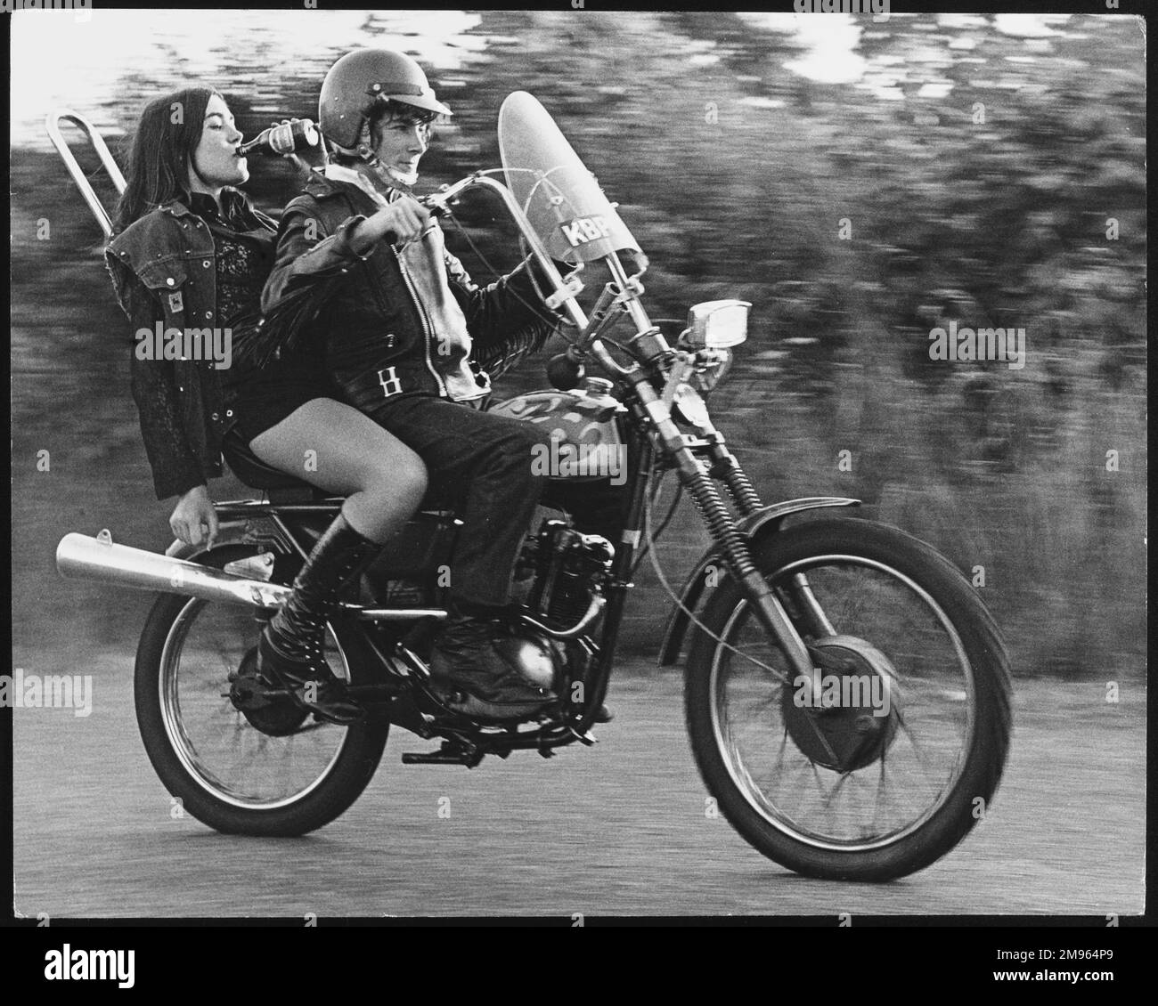Adolescenti ribelli su una moto a Charlwood, Surrey. Indossano le loro pelli e la ragazza sta girando una bottiglia di shandy! Foto Stock
