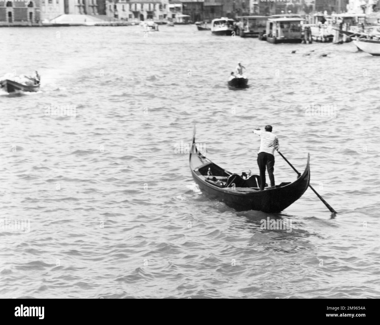 Una gondola fa la sua strada attraverso i corsi d'acqua di Venezia. Foto Stock