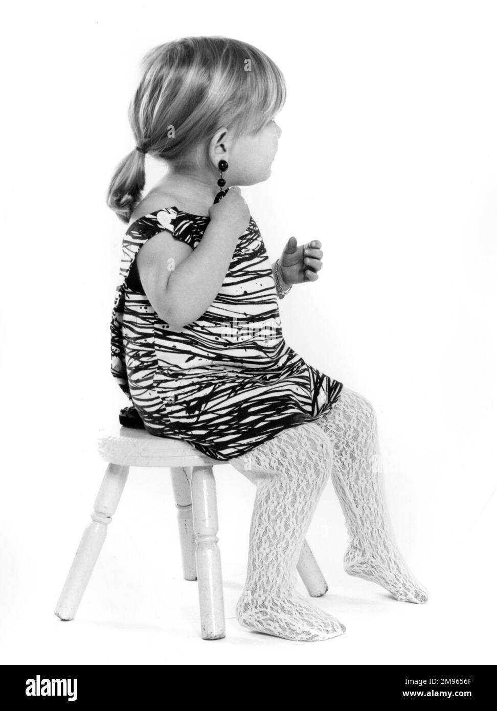 Una bambina seduta su uno sgabello. Foto Stock