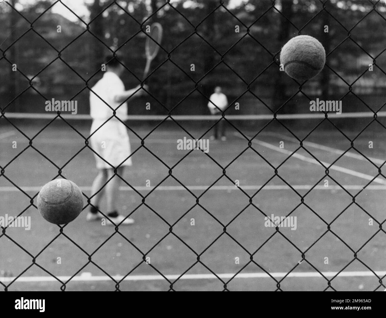 Palle da tennis alloggiate in una recinzione di filo durante una partita di tennis, Inghilterra. Foto Stock