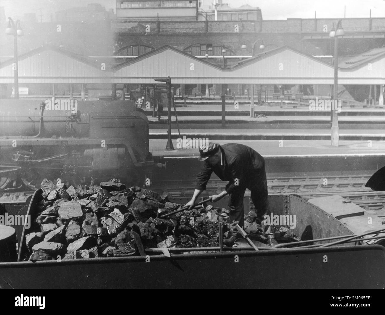 Un lavoratore ferroviario che mette il carbone in una gara, una scena a Liverpool Street Station, Londra, Inghilterra. Foto Stock