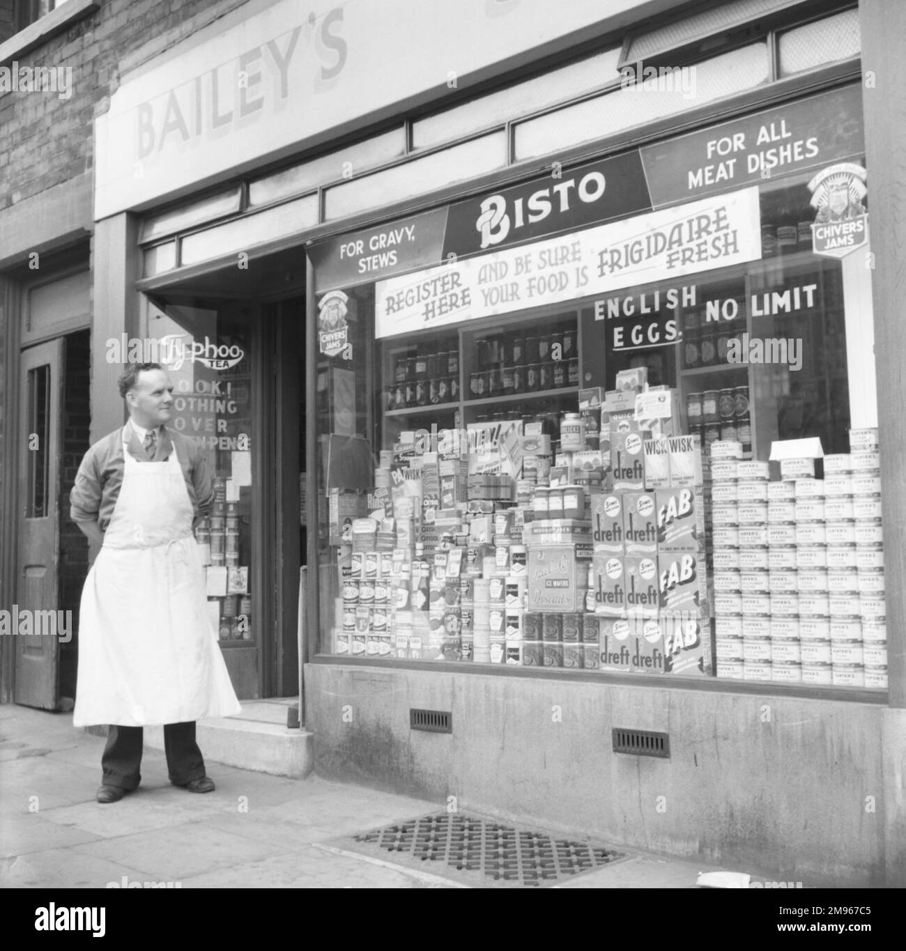 Bailey's Grocery Store e l'orgoglioso negoziante, che valuta la vetrina Weeks. Fotografia di Norman Synge Waller Budd Foto Stock