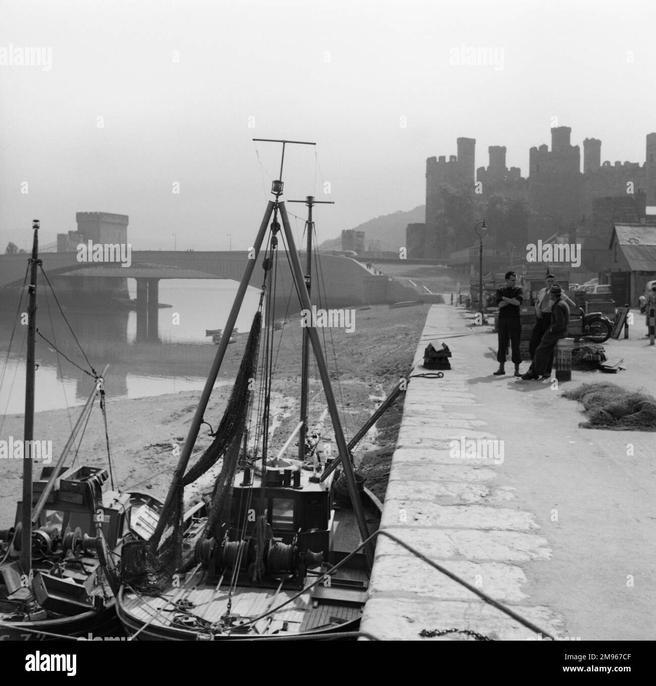 Una splendida vista suggestiva sul porto di Conwy, nel Galles del Nord, con la silhouette del Castello sullo sfondo. Fotografia di Norman Synge Waller Budd Foto Stock