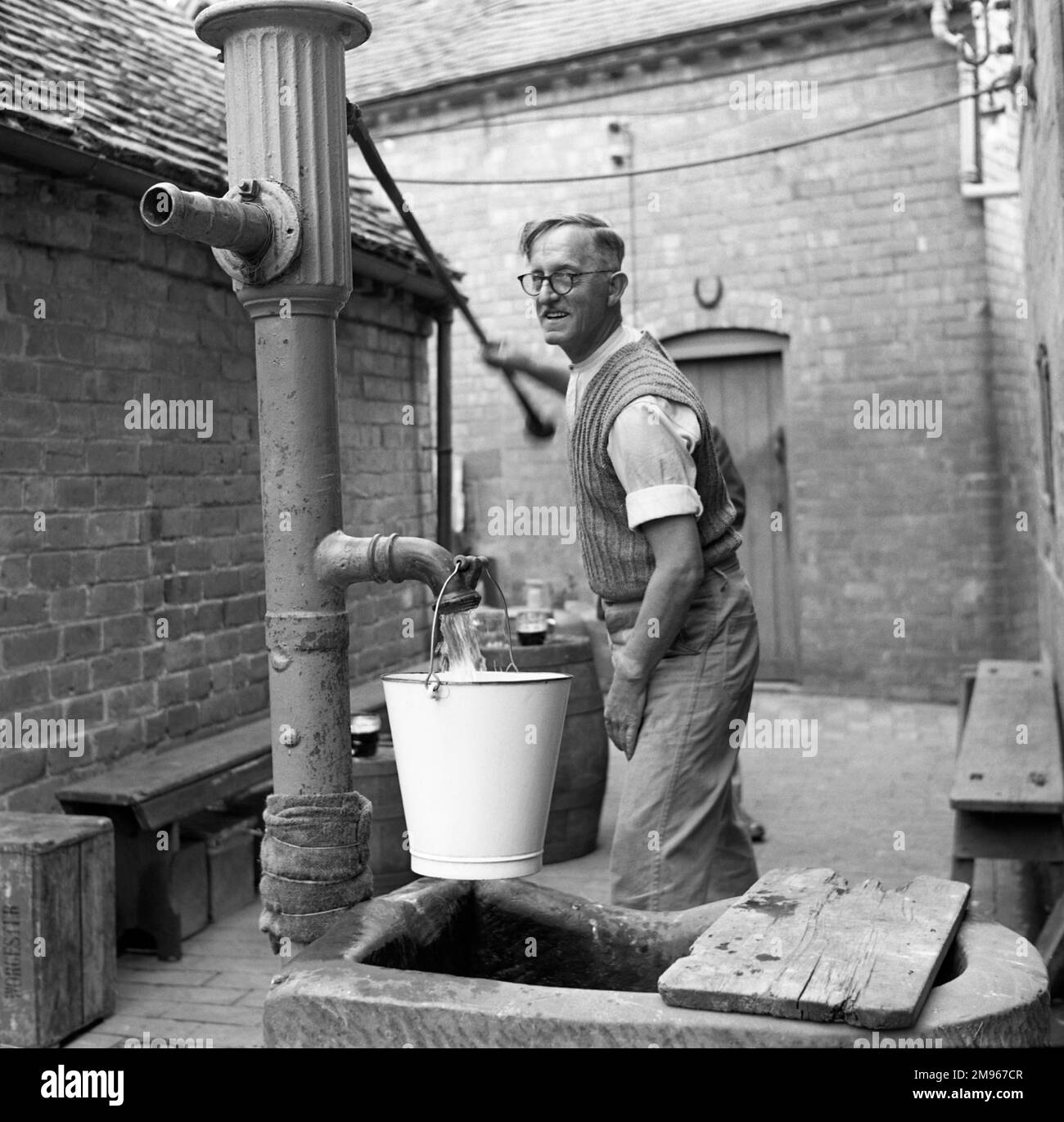 Azionare una pompa a mano al Fruiterer's Arms, Hartlebury, Worcestershire. Fotografia di Norman Synge Waller Budd Foto Stock