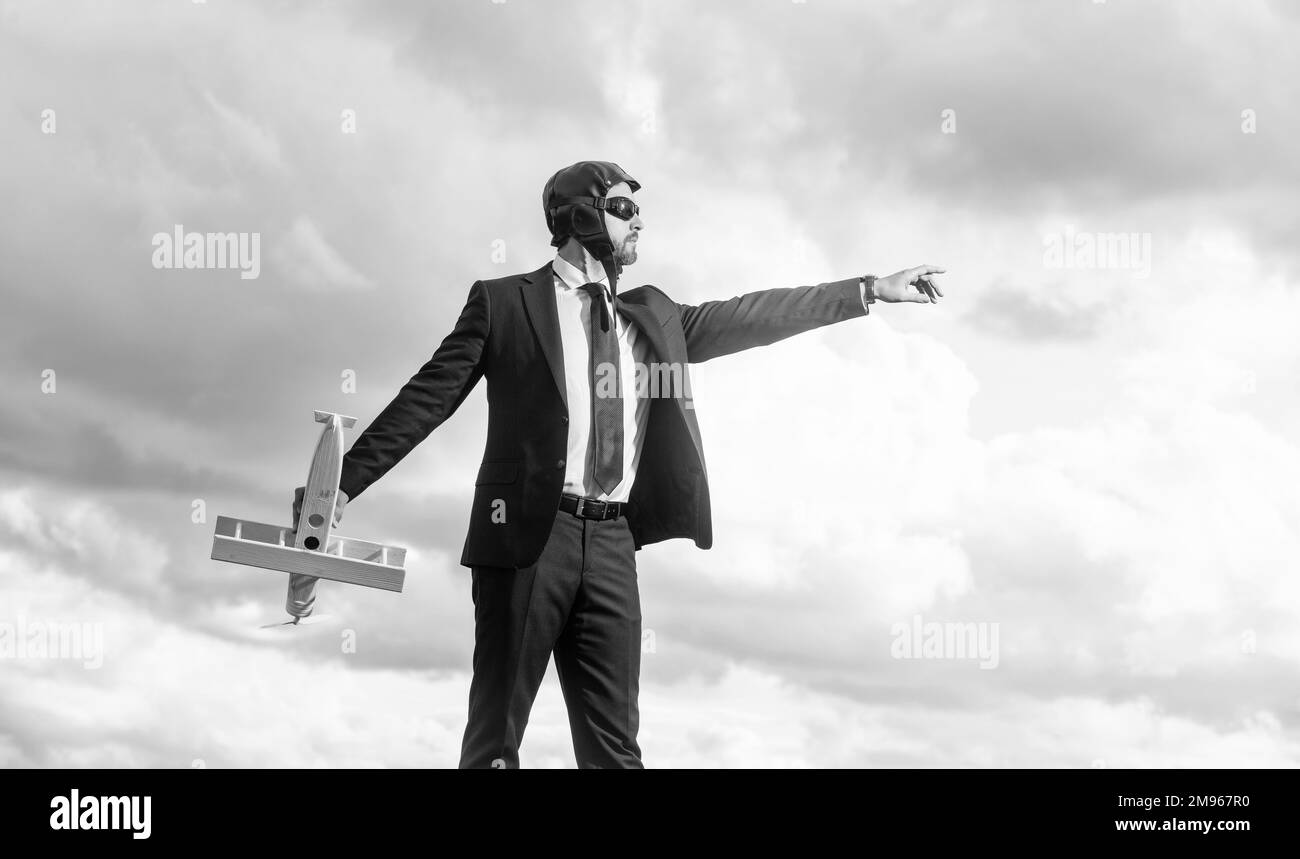 uomo d'affari in tuta e cappello pilota lancio aereo giocattolo su sfondo cielo. startup Foto Stock