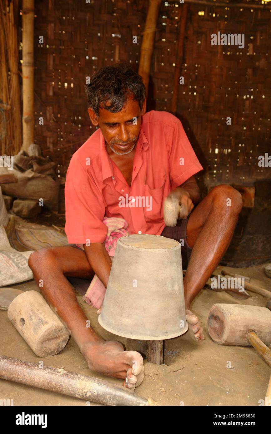 Un operaio di metallo fa una pentola di ottone con metodi tradizionali a Matiari, un villaggio nel Bengala Occidentale, India. Foto Stock