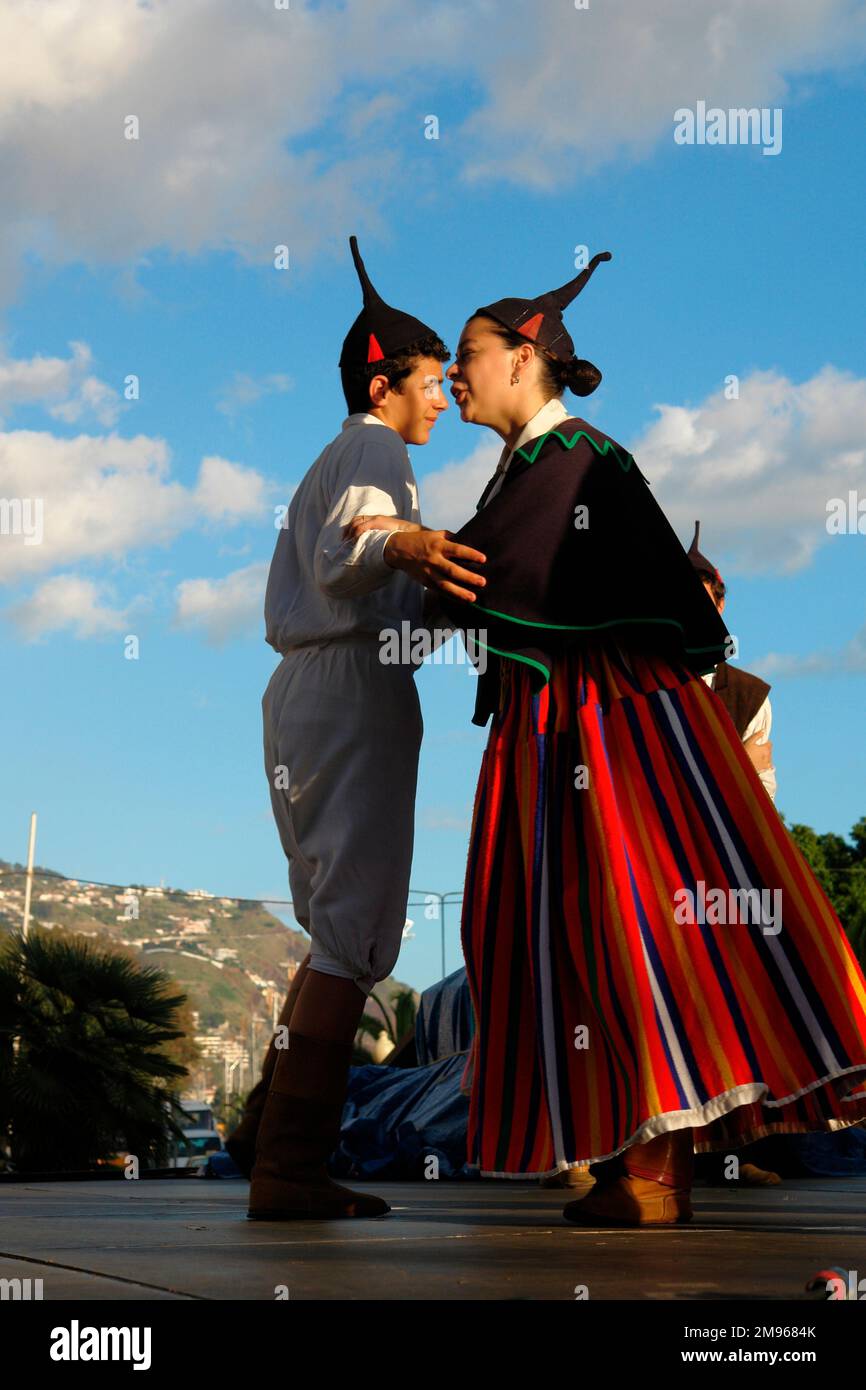 Due membri di un gruppo folcloristico di Boa Nova, visto qui ballare a Funchal, la capitale di Madeira. Indossano costumi tradizionali, tra cui i cappucci neri del cranio con punte. La donna indossa una gonna a lunghe strisce. Foto Stock