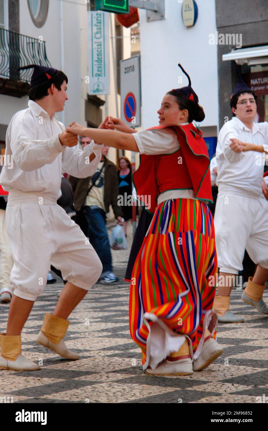 Due membri di un gruppo folcloristico di Gaula, visto qui ballare a Funchal, la capitale di Madeira. La coppia indossa un costume tradizionale, compresi i cappucci neri del cranio con punte. La donna indossa prevalentemente rosso, compresa una gonna a righe lunghe. L'uomo è vestito di bianco. Foto Stock