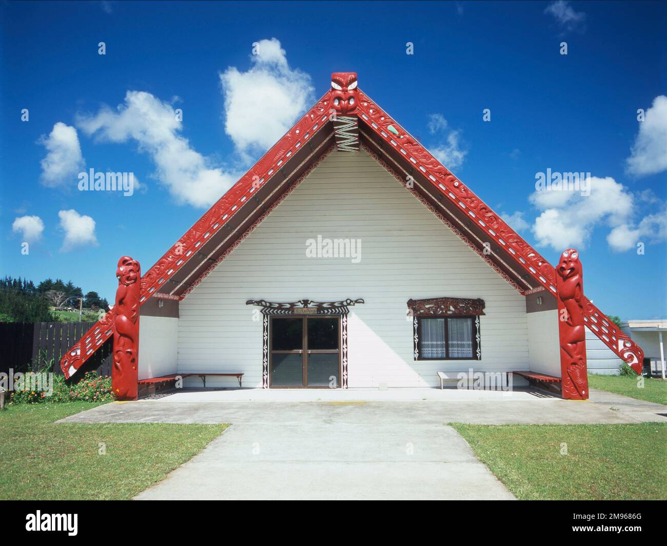 Una tradizionale sala riunioni Maori (o Marae) a Kaitaia, vicino Pukepato, nell'estremo nord dell'Isola del Nord, Nuova Zelanda. E' decorata con distintive sculture rosse. Foto Stock