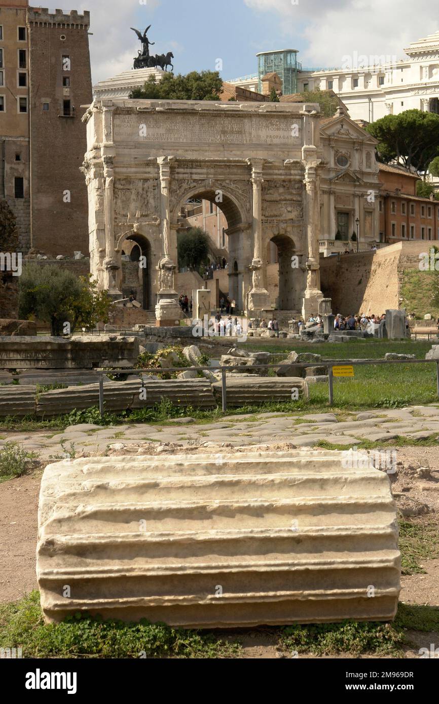 Veduta dell'Arco di Settimio Severo a Roma. Si tratta di un arco trionfale di marmo bianco nel Foro Romano, dedicato nel 203 d.C. a commemorare le vittorie partiane dell'imperatore Settimio Severo e dei suoi due figli, Caracalla e Geta, nelle due campagne contro i Parthiani. In primo piano è presente una sezione di una colonna scanalata. Foto Stock