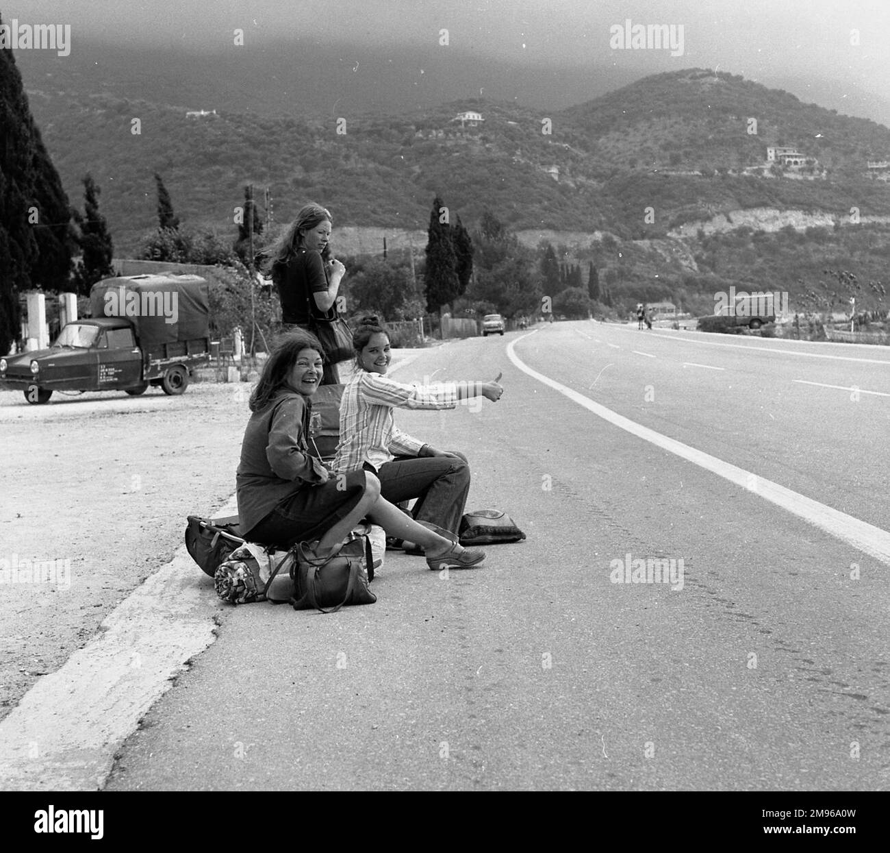 Tre giovani donne intagliano-escursioni dal lato di una strada a Ipsos, Corfù, Grecia. Foto Stock
