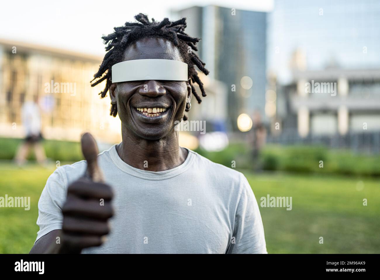 Uomo adulto africano che indossa occhiali hi-tech per la realtà aumentata, occhiali futuristici stile di vita intelligente, un segno di pollice Foto Stock