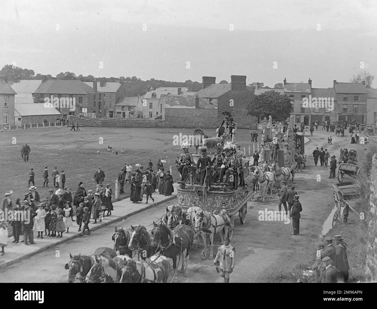 Street scene, che mostra parte della parata del Circus di Sanger durante una visita a Haverfordwest, Pembrokeshire, Dyfed, Galles del Sud. La prima di queste due elaborate carrozze trainate da cavalli comprende un leone e un agnello, con i cavalieri vestiti in costumi di fantasia. Le persone sui marciapiedi si fermano e guardano. Sanger fu un famoso impresario del circo, che a partire dagli anni '1850s organizzò spettacoli spettacolari in grandi locali in tutto il paese. Foto Stock