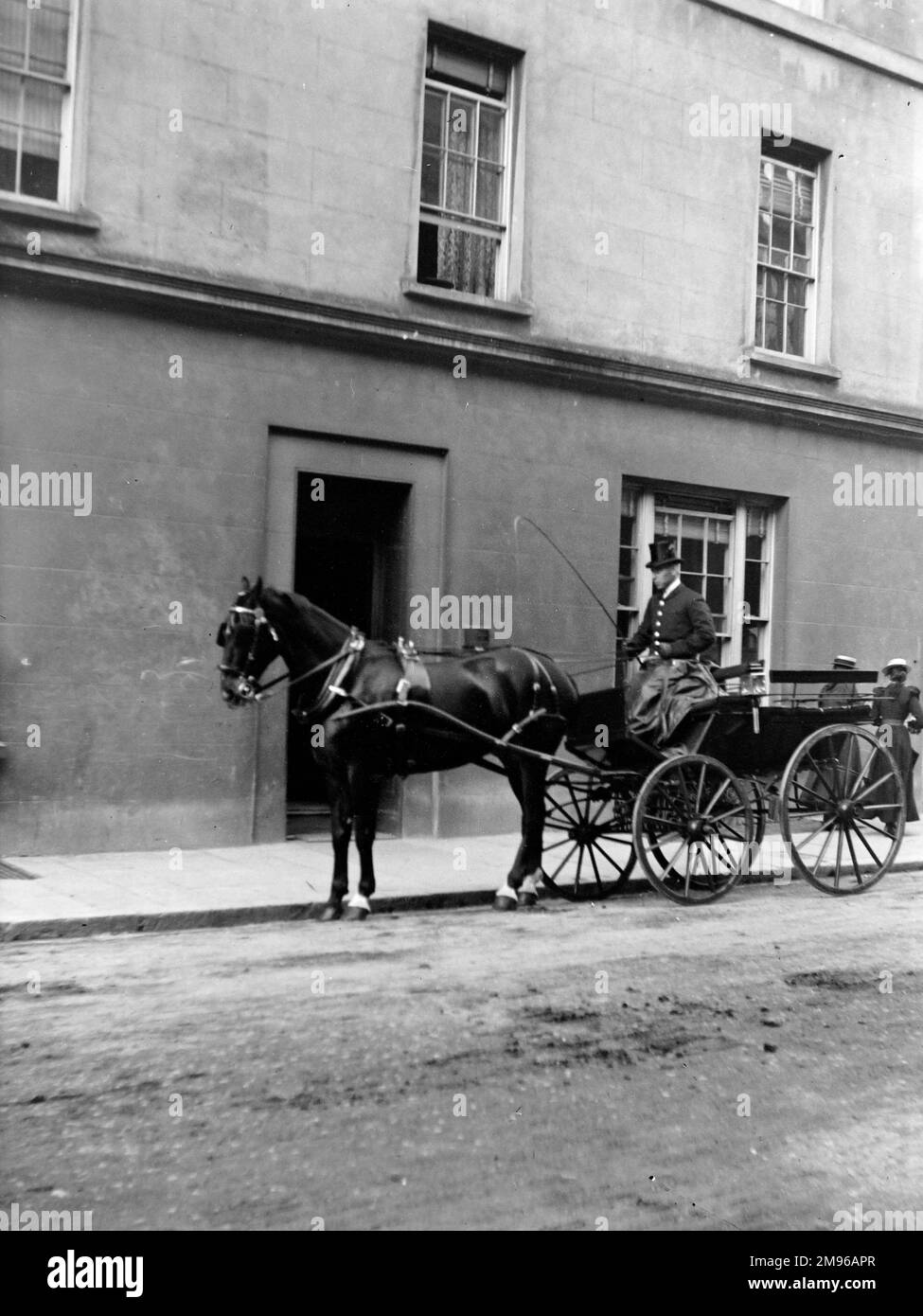 Un cavallo piuttosto impressionante e una carrozza aperta, con il suo autista elegantemente vestito, parcheggiato fuori da un edificio in Quay Street, Haverfordwest, Pembrokeshire, Dyfed, Galles del Sud. Foto Stock