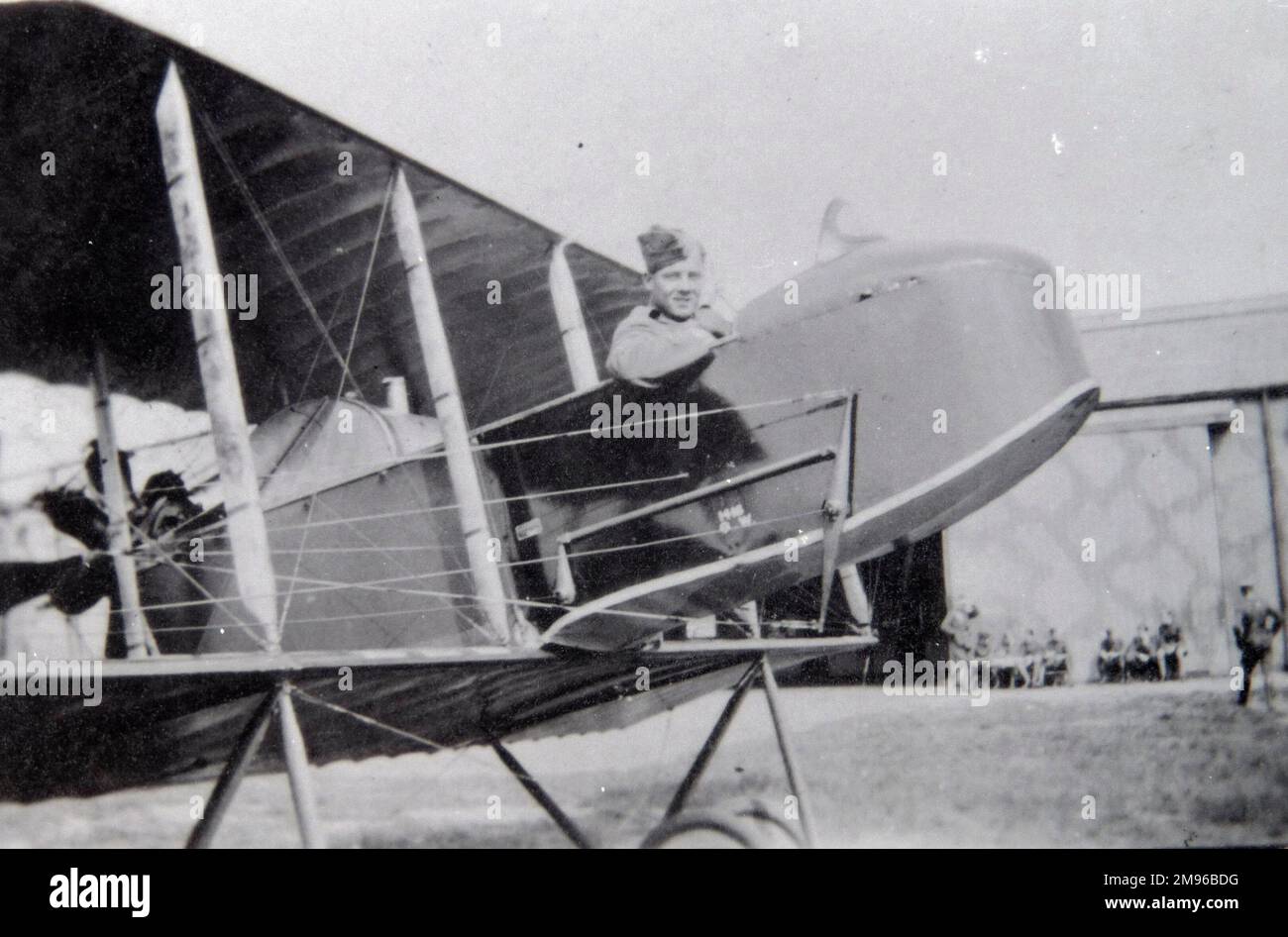Un pilota della prima guerra mondiale siede ai comandi del suo aereo Henri Farman HF.20, su un campo aereo. Altri membri dell'equipaggio possono essere visti sullo sfondo. Foto Stock