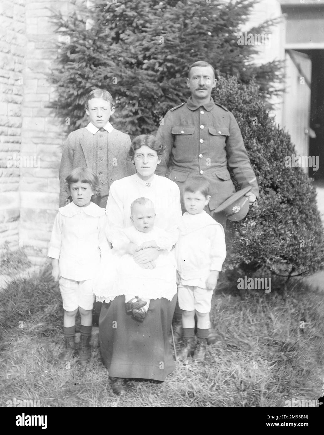 Una foto di gruppo di famiglia in un giardino, con il padre in uniforme, intorno al tempo dello scoppio della prima guerra mondiale. Foto Stock