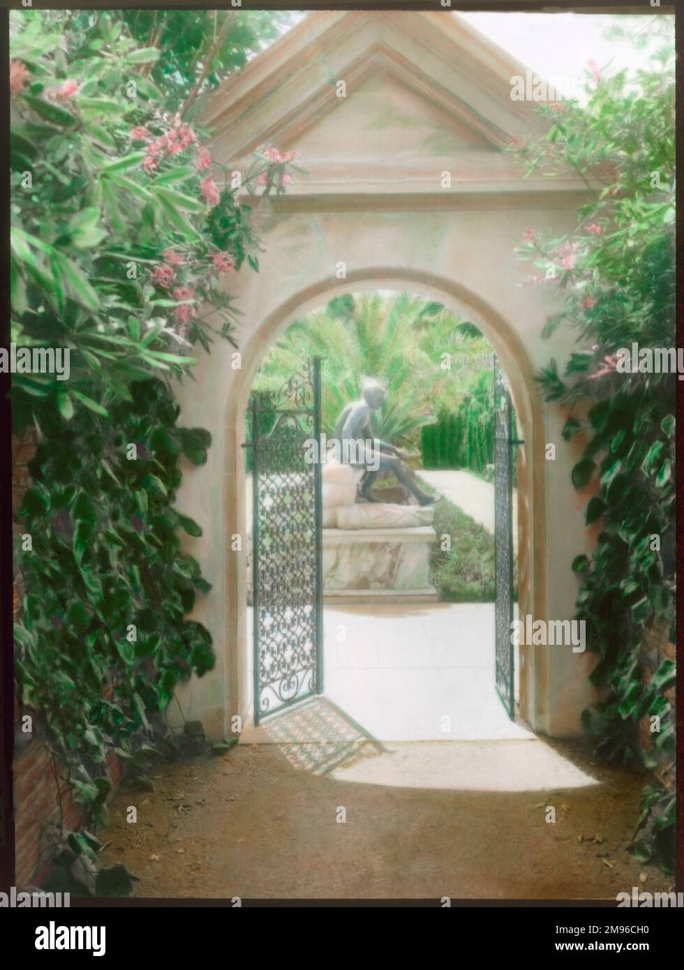 Una porta aperta in un giardino all'italiana. La statua di un ragazzo è incorniciata all'interno dell'arco. Foto Stock