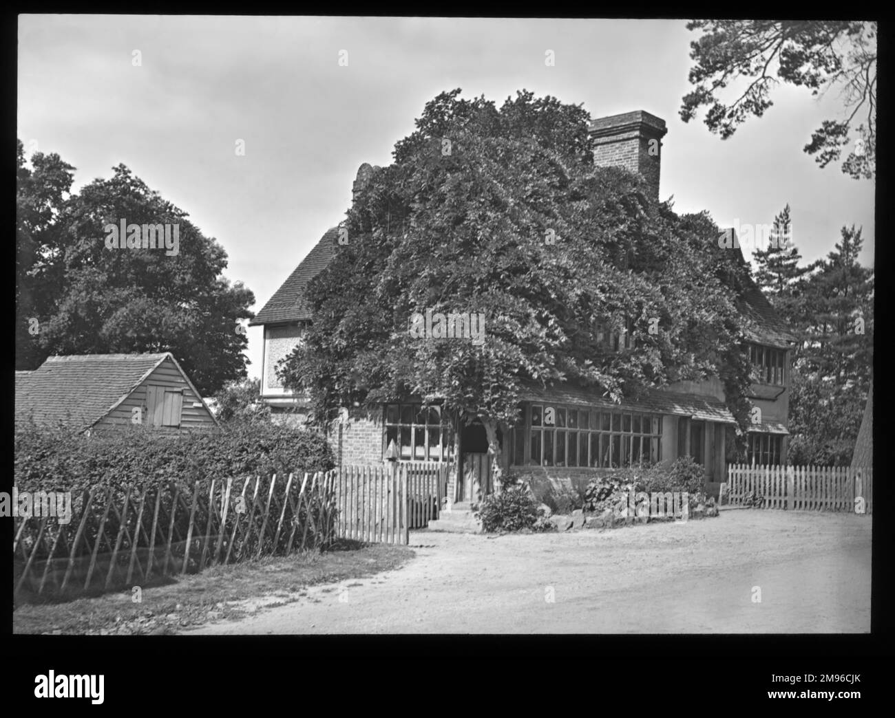 Una casa non identificata su una strada di campagna, in parte oscurata da un grande albero. Foto Stock