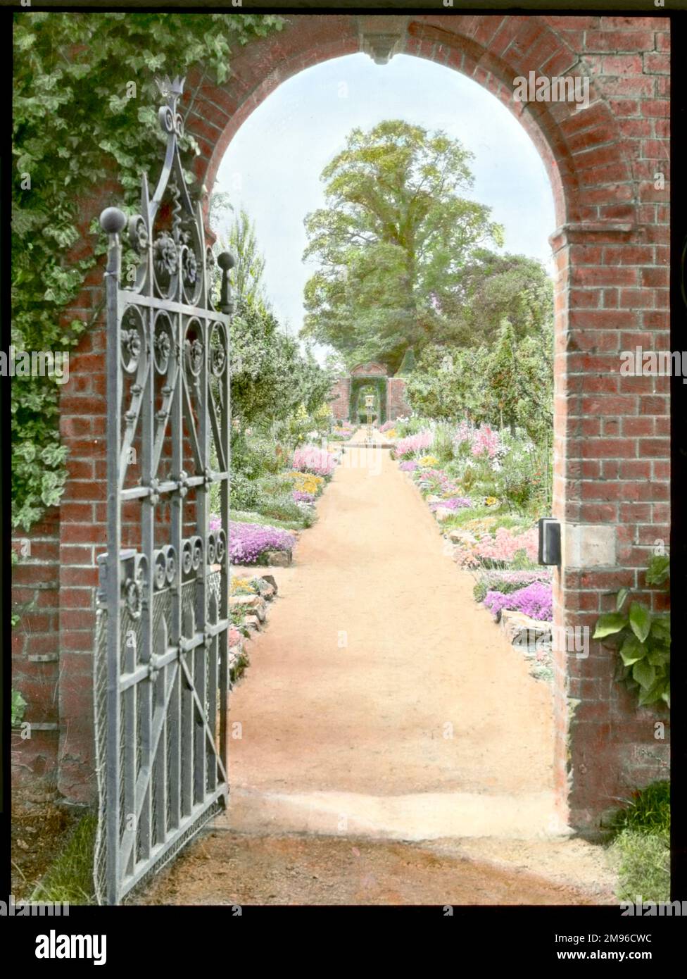 Vista sui giardini di Aldenham House, vicino a Borehamwood, Hertfordshire, visto attraverso un cancello aperto in un arco. Foto Stock