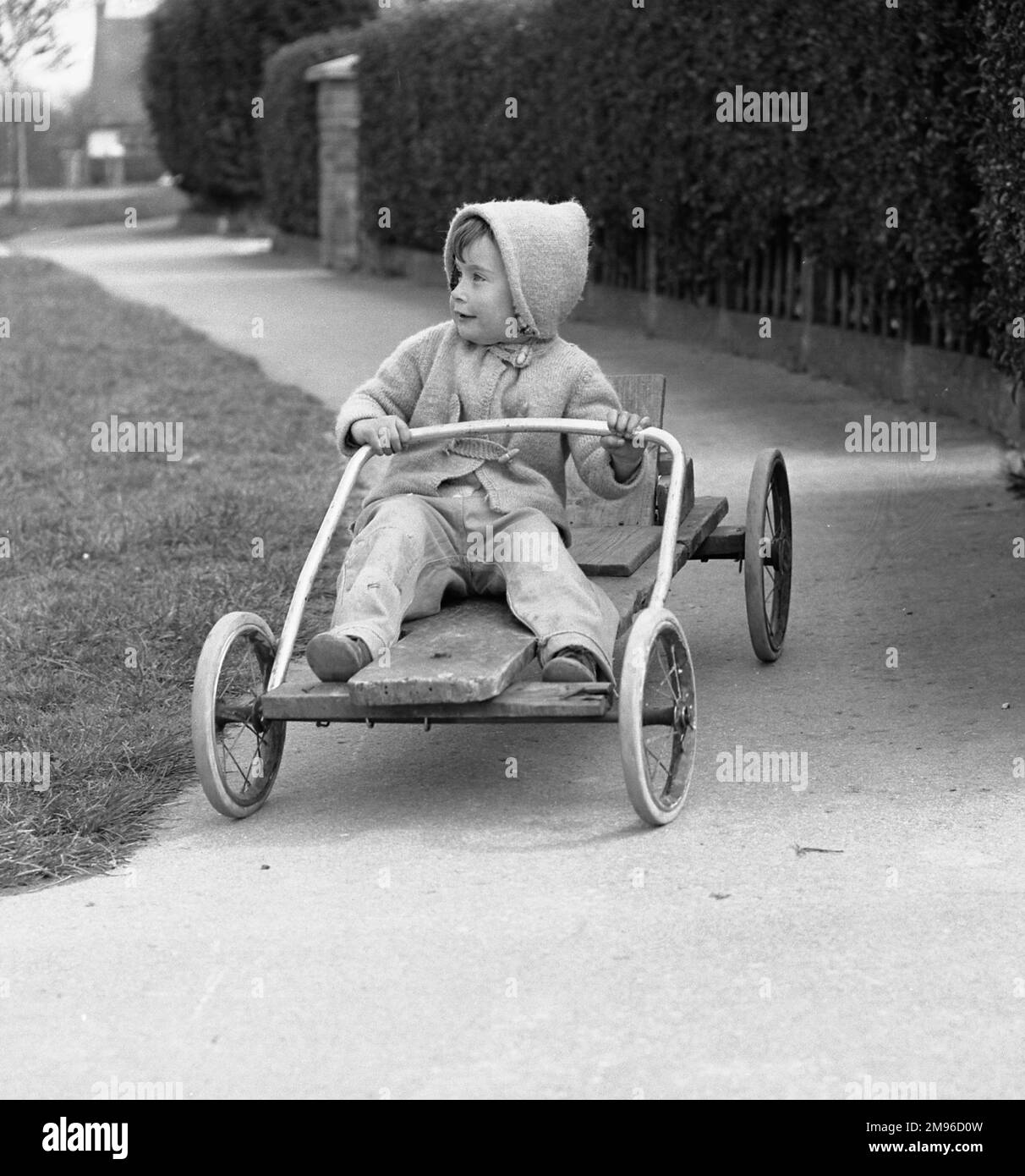 Un ragazzino che cavalca su un go-kart negozia una curva nel sentiero. Foto Stock