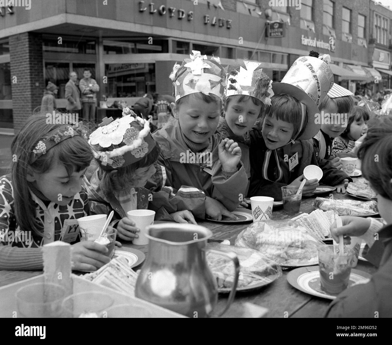 Un gruppo di bambini si diverte a prendere il tè in una strada a Horley, Surrey, per celebrare il Giubileo d'argento della Regina Elisabetta II. Le coppe di carta sono decorate con Union Jacks. Foto Stock