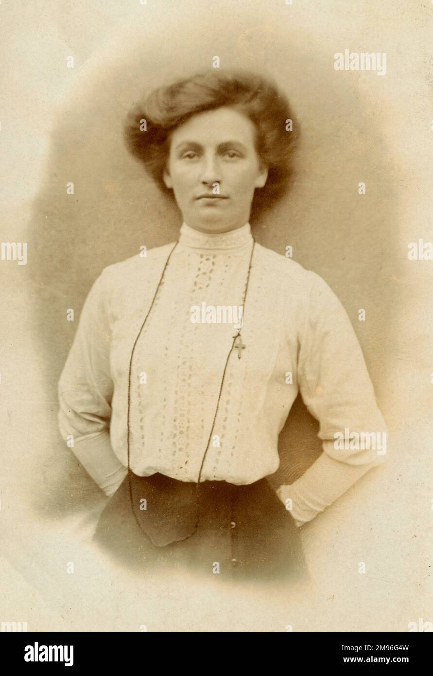 Donna che indossa una blusa a collo alto, broderie-anglaise e spilla crocifissa. Foto Stock