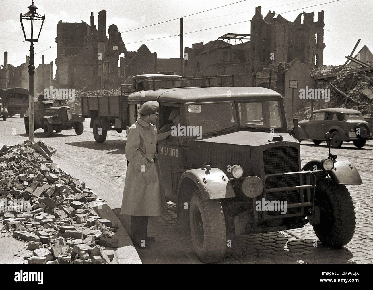 Una bomba ha danneggiato la strada in Germania durante la seconda guerra mondiale, con edifici in rovina, mucchi di macerie e alcuni veicoli sulla strada. Foto Stock
