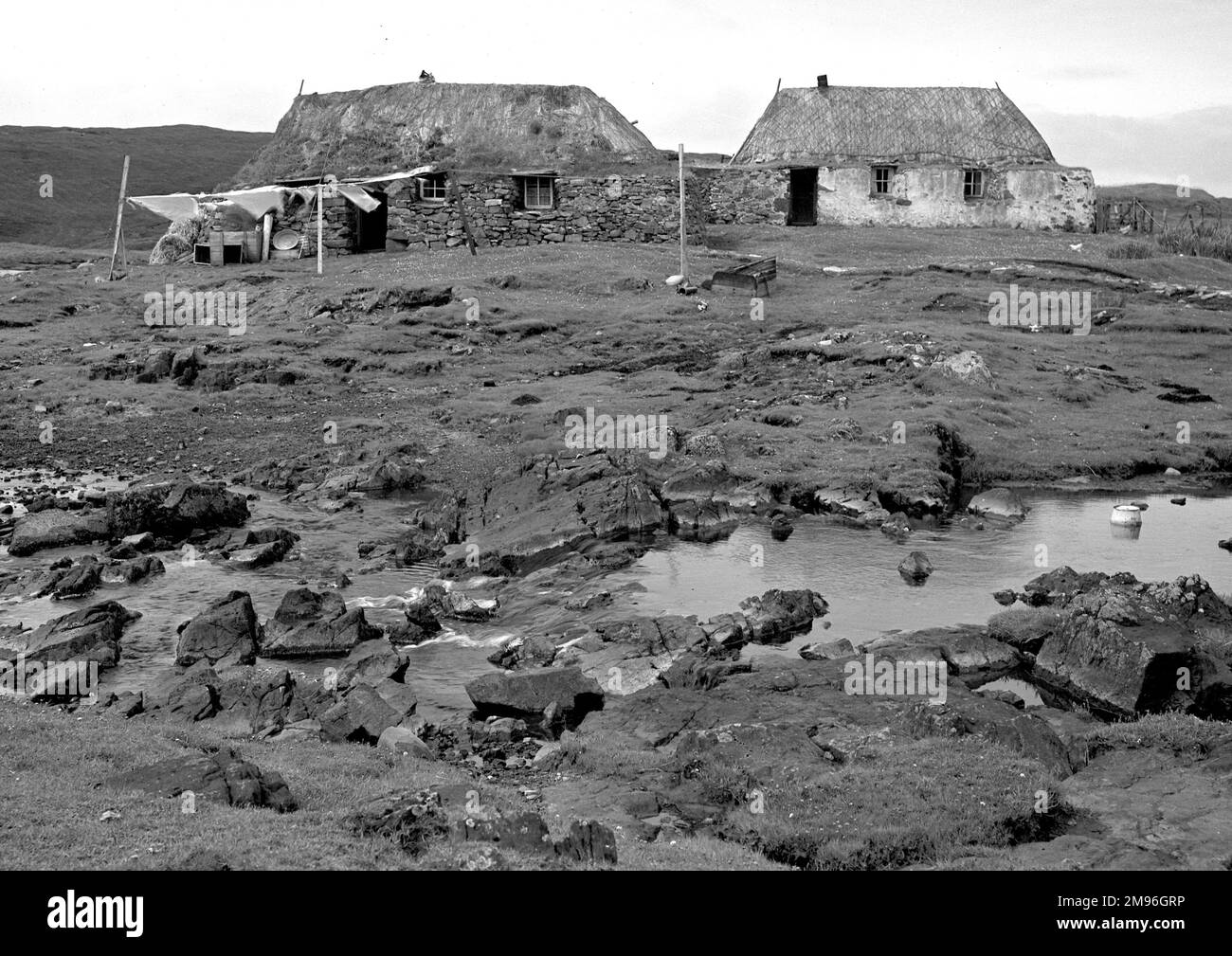 Due cottage rustici in un paesaggio desolante, con lavaggio flapping su una linea di vestiti, a Timsgarry, Uig, Isola di Lewis, Ebridi esterne, Scozia. Foto Stock