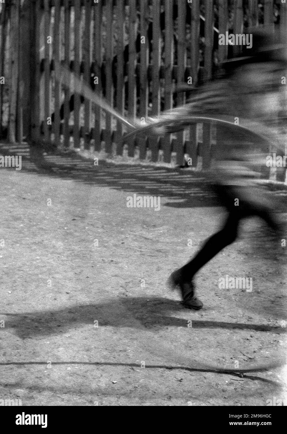 Un'immagine sfocata di un bambino che gioca con un cerchio e bastone -- evidentemente muovendosi avanti a velocità! Foto Stock