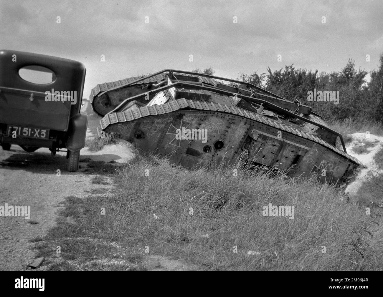 Un carro armato tedesco della prima guerra mondiale in un fosso poco profondo al lato di una strada alla fine della guerra, con una macchina che passa accanto. Foto Stock