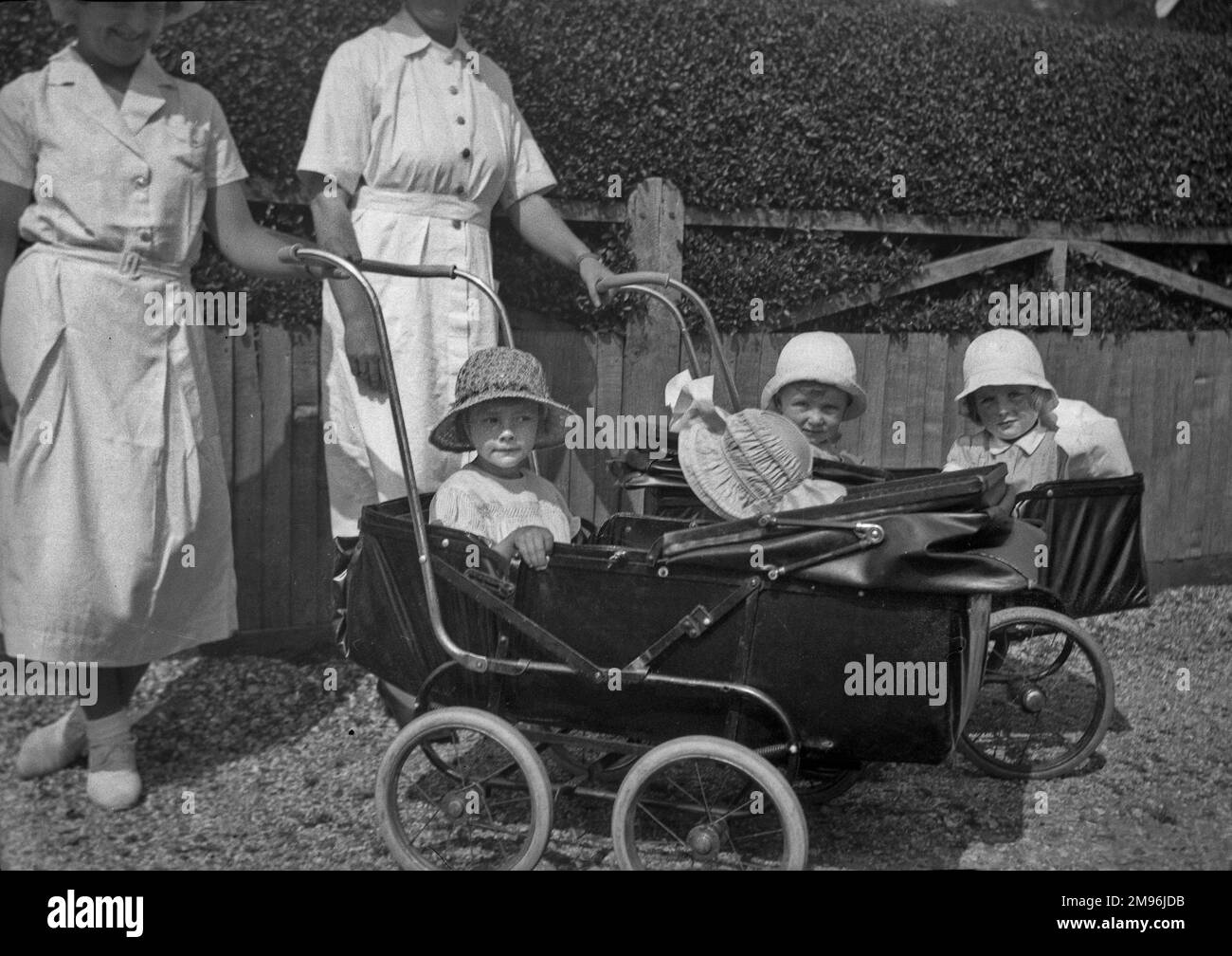 Due pannie con quattro bambini in passeggini. Foto Stock