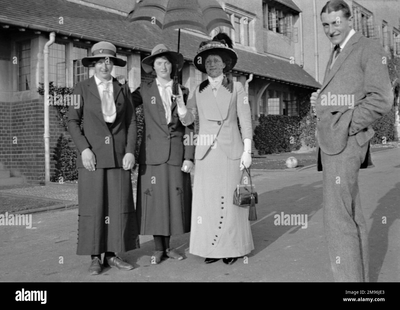 Un uomo e tre donne in posa per la loro foto di fronte a una casa. Foto Stock