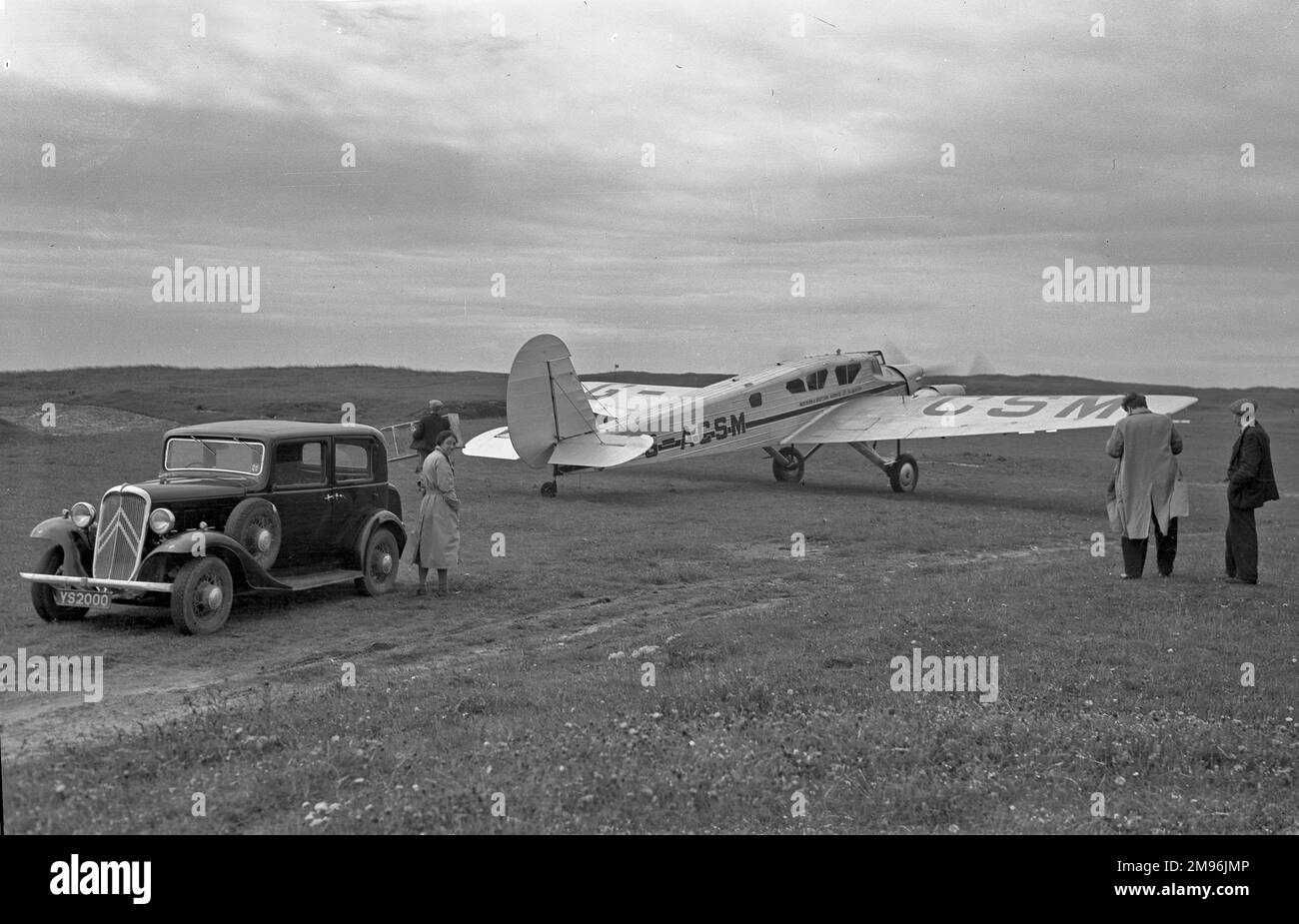 Persone in un campo in Scozia con un'auto e un aereo leggero. Il G-ACSM era uno Spartan Cruiser II con tre motori, gestito dalla Northern & Scottish Airways Ltd, poi dalla Scottish Airways Ltd, a Renfrew. Foto Stock