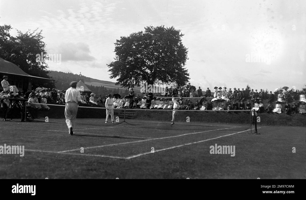 Partita di tennis edoardiana in un luogo sconosciuto, ma una buona affluenza e un colpo d'azione impressionante data la tecnologia del tempo Foto Stock