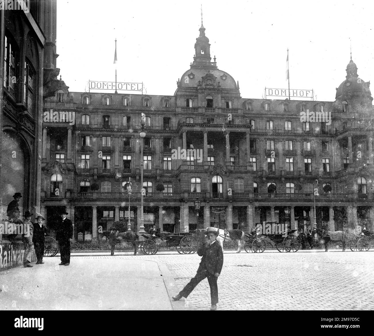 Colonia, il Dom Hotel che è ancora in corso oggi. I ragazzi guardano la novità di un cameriere mentre le carrozze aspettano all'esterno del prestigioso hotel. Foto Stock