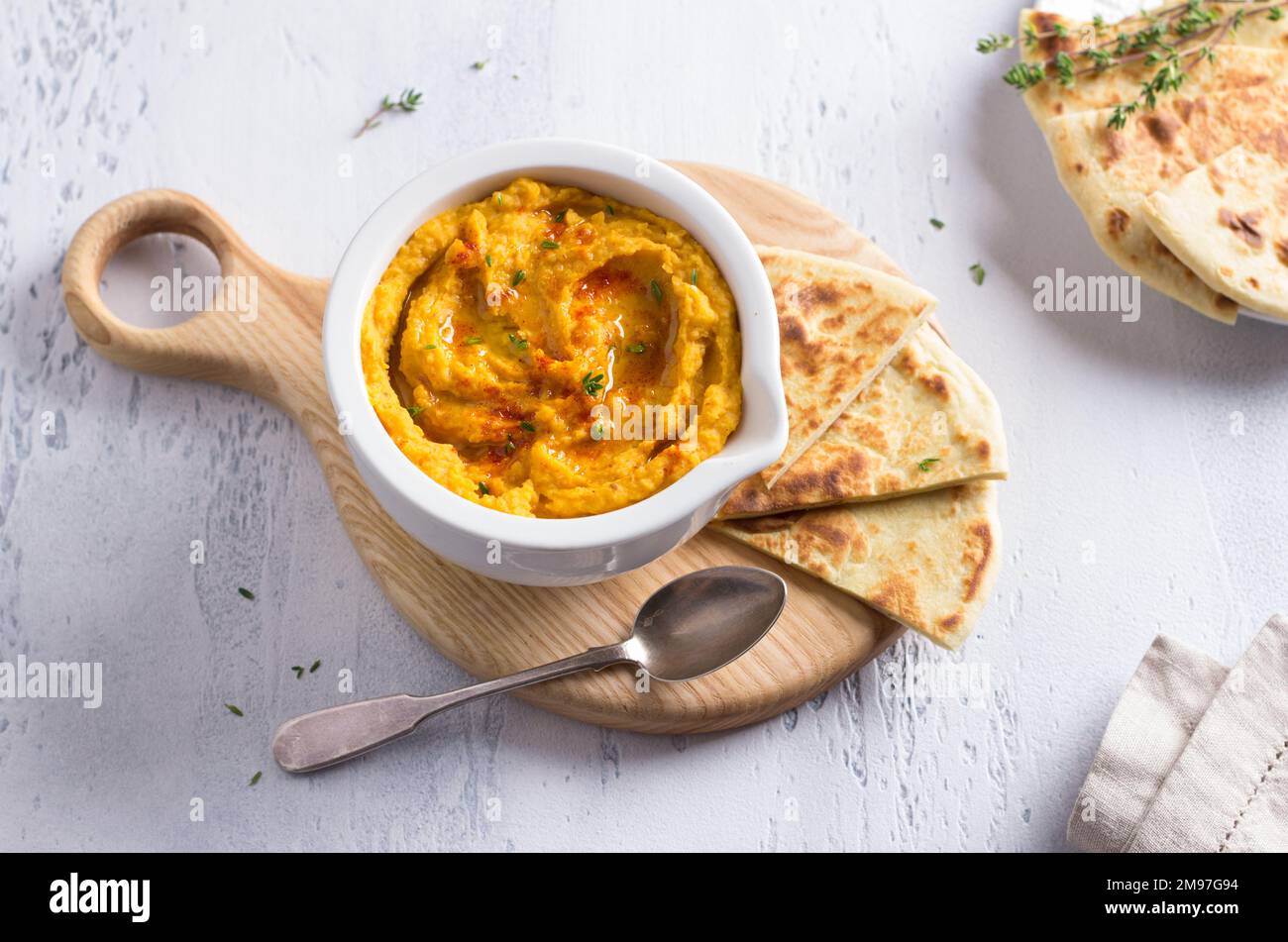 Delizioso hummus di fagioli fatti in casa con zucca al forno, tahina e spezie con pane piatto su sfondo azzurro, vista dall'alto Foto Stock