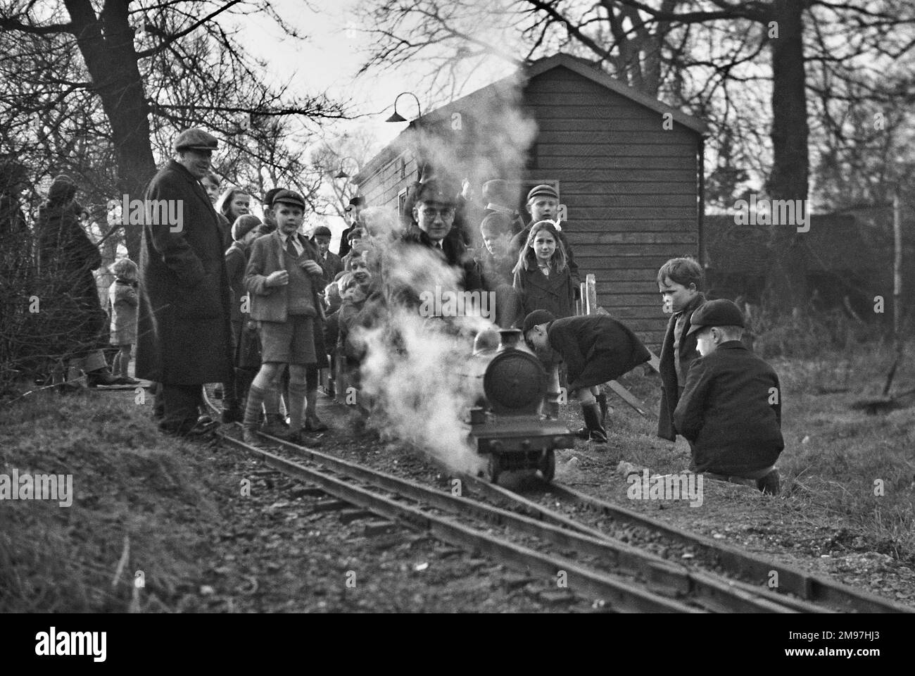 I bambini si sono riuniti intorno a un treno a vapore in miniatura. Foto Stock