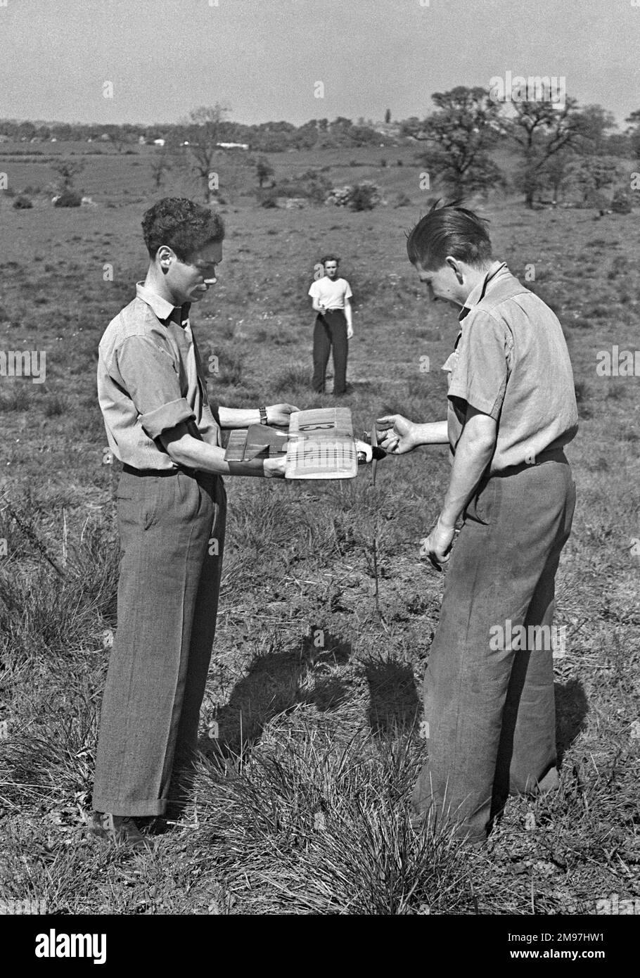 Tre uomini in possesso di un aereo modello in un campo, pronti a testare le sue capacità di volo. Foto Stock