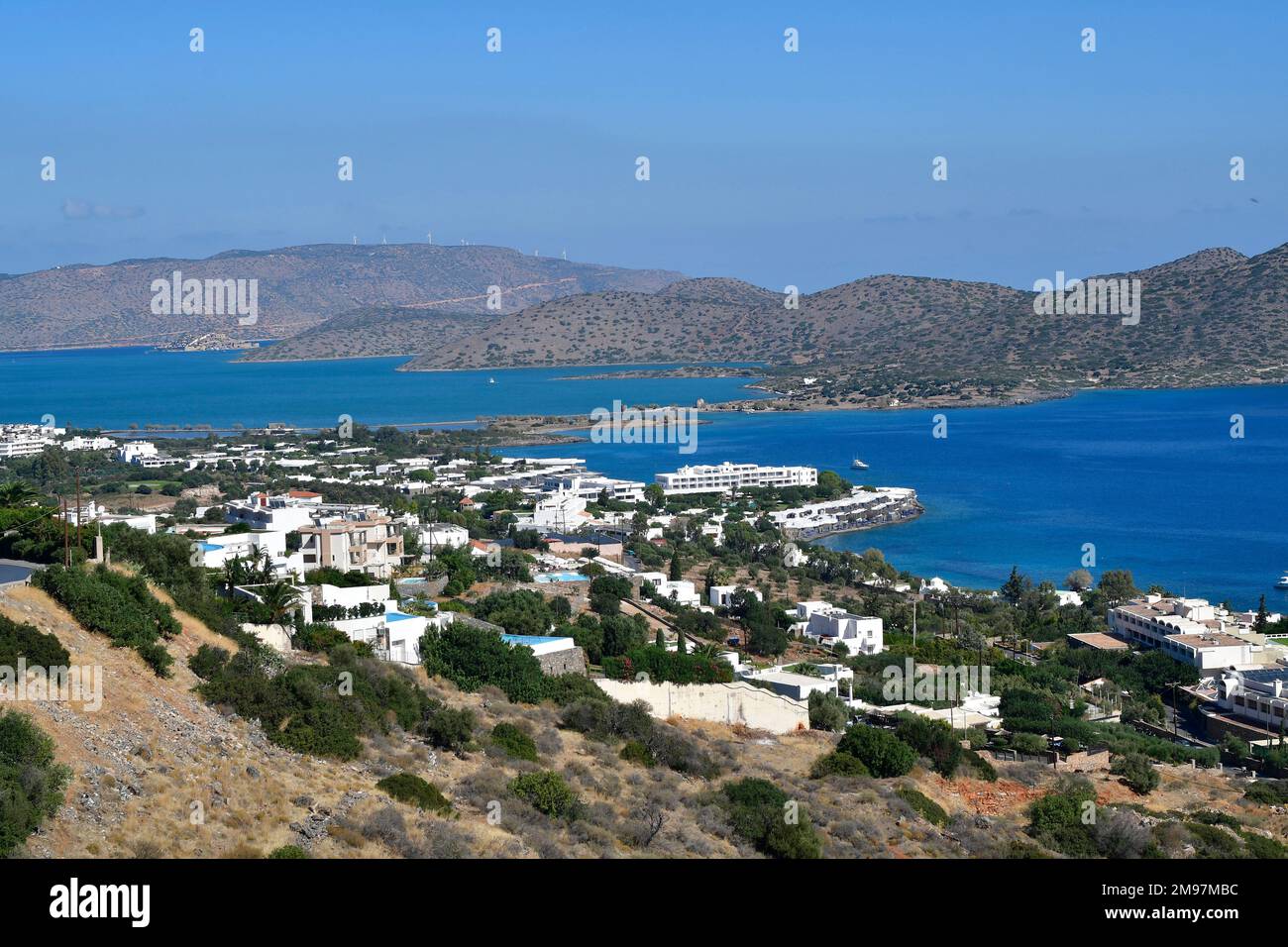 Grecia, Creta, complesso alberghiero sul Mare di Creta con la stretta strada sopraelevata per la penisola di Spinalonga, sullo sfondo l'ex fortezza veneziana An Foto Stock