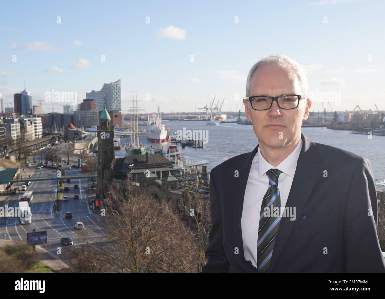 17 gennaio 2023, Amburgo: Nico Nolte, capo del Dipartimento dell'Ordine del Mare, si trova su un balcone dopo la conferenza stampa annuale dell'Agenzia federale marittima e idrografica (BSH). Il Landungsbrücken, il Überseebrücke e l'Elbphilharmonie sono visibili sullo sfondo. La BSH non vede alcuna possibilità di accelerare il processo di approvazione del dumping del limo Elbe nella zona economica esclusiva. Amburgo è sotto una certa pressione quando si tratta di smaltimento del limo, perché l'accordo sullo scarico del limo sul marcatrice E3 vicino a Helgoland è limitato nel tempo e nei paesi vicini dello Schleswig-ho Foto Stock