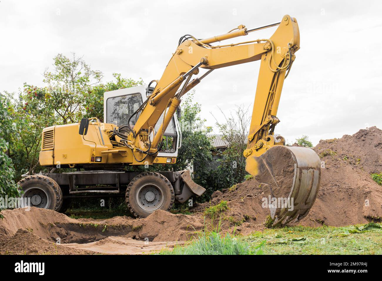 Un secchio di escavatore con un mucchio di sabbia e un fondo terreno. Lavori industriali sul cantiere. Foto Stock