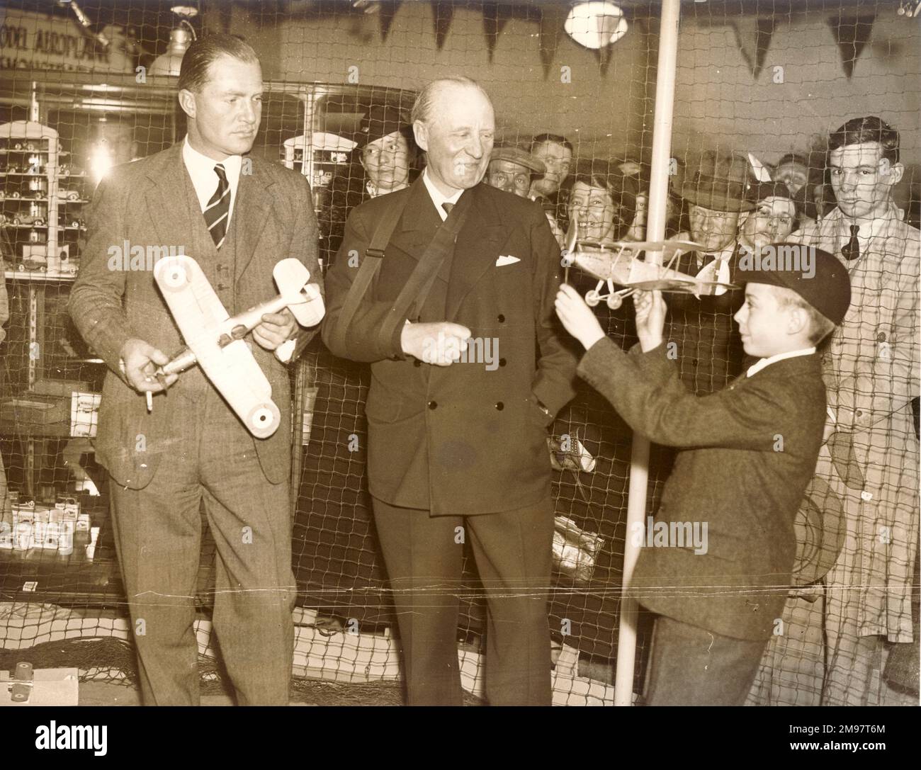 C.W.A. Scott, a sinistra, e Sir Harry Brittain in una mostra di modellisti a Selfridges, assistono a una dimostrazione di Bruce Young, di 11 anni, che aveva una delle più belle collezioni di modellini di aeroplani del paese, tutte realizzate con le sue mani. 22 ottobre 1936. Foto Stock