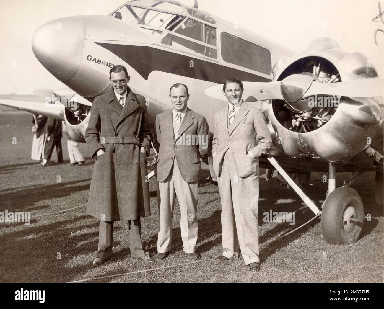 Velocità aerea AS.6 inviato II - G-AENA 'Gabrielle'. Tre degli equipaggi di quattro sono stati in piedi davanti, prima di partire in Inghilterra (Portsmouth) per il Sud Africa (Johannesburg) per il Trofeo Schlesinger a settembre / ottobre 1936. Max H. Findlay comprò un convoglio di Cheetah-engined Envoy II, G-AENA, e lo fece equipaggiato con serbatoi speciali a lungo raggio che danno una capacità totale, oltre al tankage standard di 78 galloni, di circa 116 galloni di combustibile. Nominato Gabrielle, e con (i superstiziosi erano veloci da notare) la gara numero 13, l'inviato ha anche portato Ken Waller come secondo pilota, A. H. Morgan come radio Foto Stock