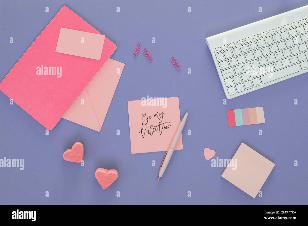 Vista dall'alto di una tastiera per computer, note adesive, caramelle a forma di cuore e una nota con le parole Be My Valentine Foto Stock