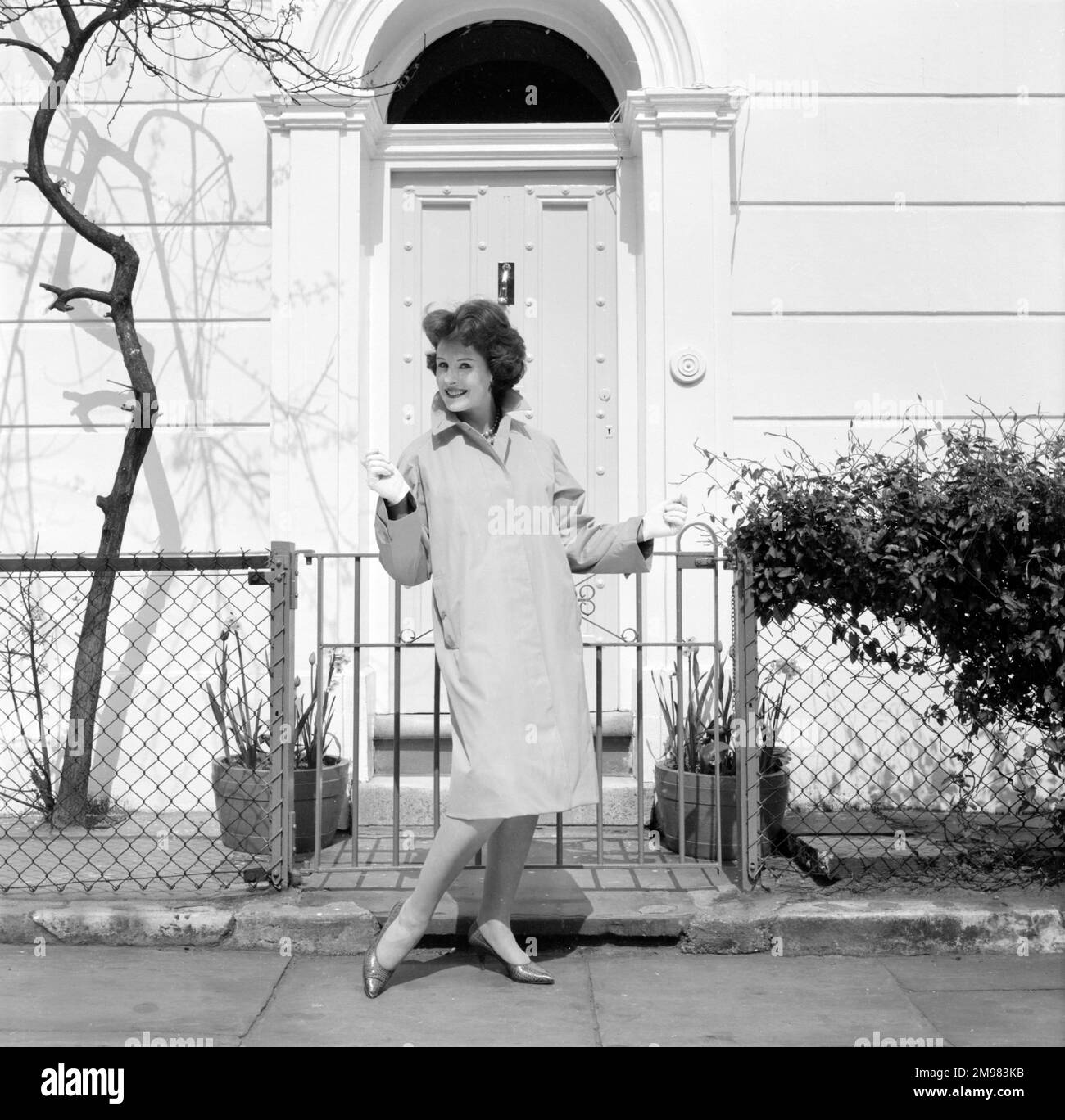 Pubblicità per Burberry cappotti -- modello femminile in posa fuori casa in stile georgiano. Foto Stock