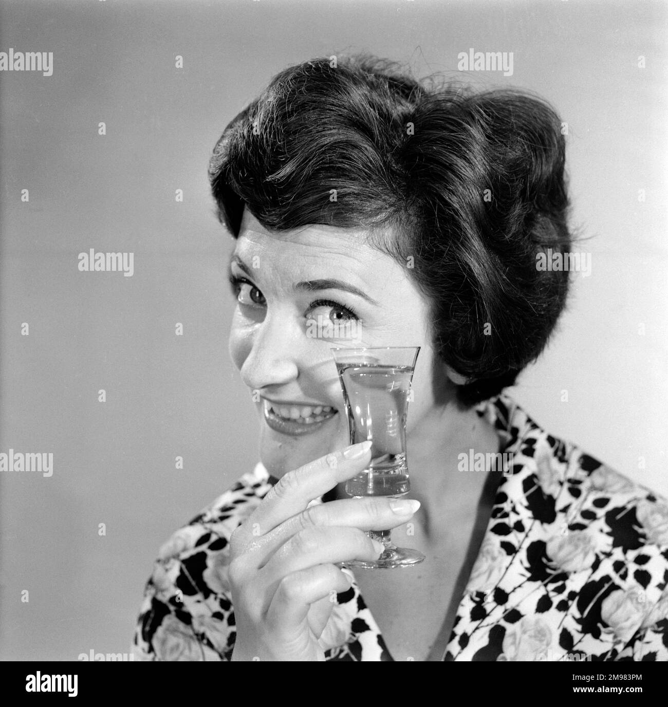 Pubblicità per lo sherry dell'emu -- modello femminile sorridente (Yvonne Marsland) che tiene su un vetro. Foto Stock