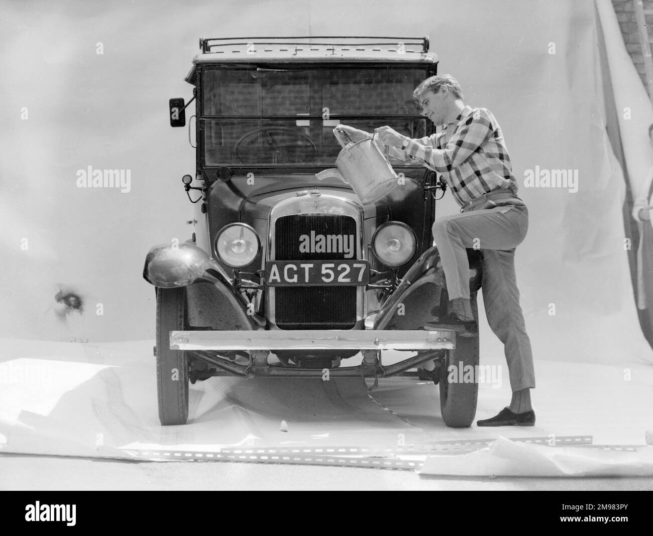 Pubblicità per petrolio di benzolo nazionale -- modello maschio come acqua di versamento meccanica in un radiatore di automobile. Foto Stock